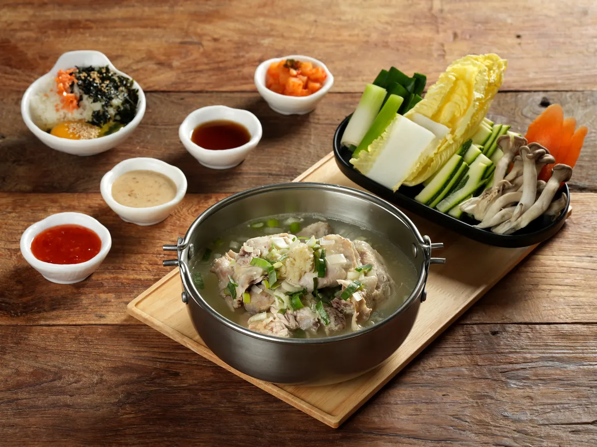 진한 닭 육수 냄비와 채소 접시, 소스가 차려진 상