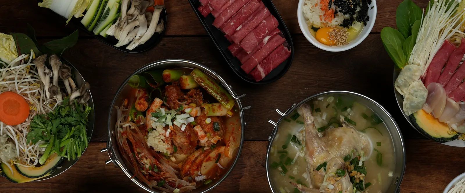 위에서 내려다본 샤브샤브 한 상: 여러 냄비와 채소, 소고기